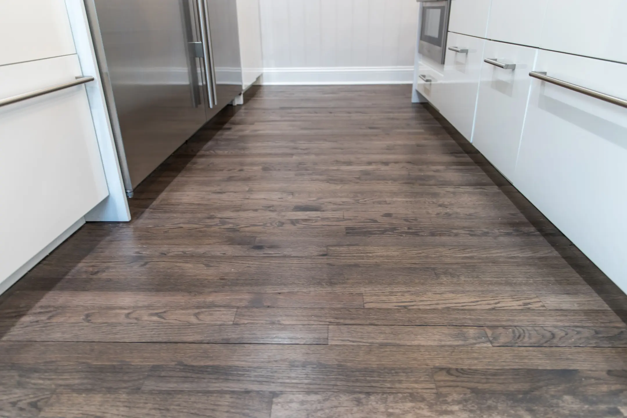 Dark wood hardwood floors in a newly renovated white cabinet modern kitchen.