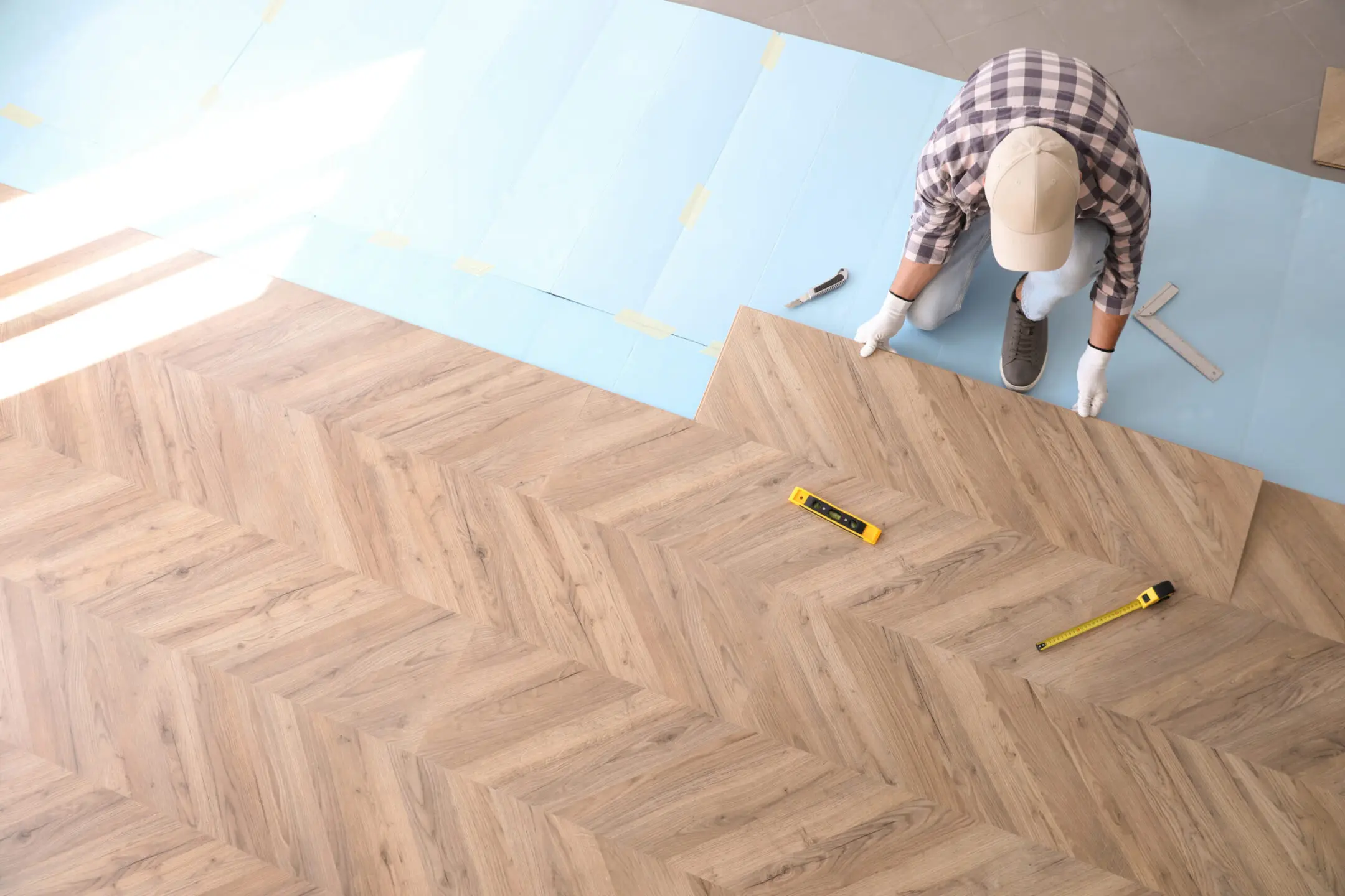 Worker installing laminated wooden floor indoors, above view