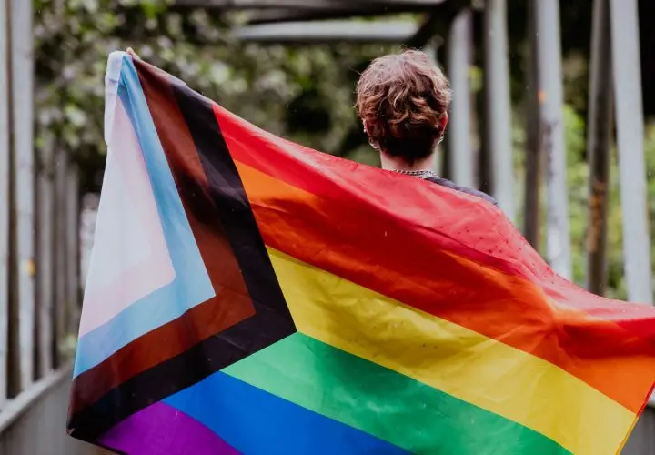 canva-person-holding-a-progress-pride-flag-outdoors--MAEkyhLUFMo
