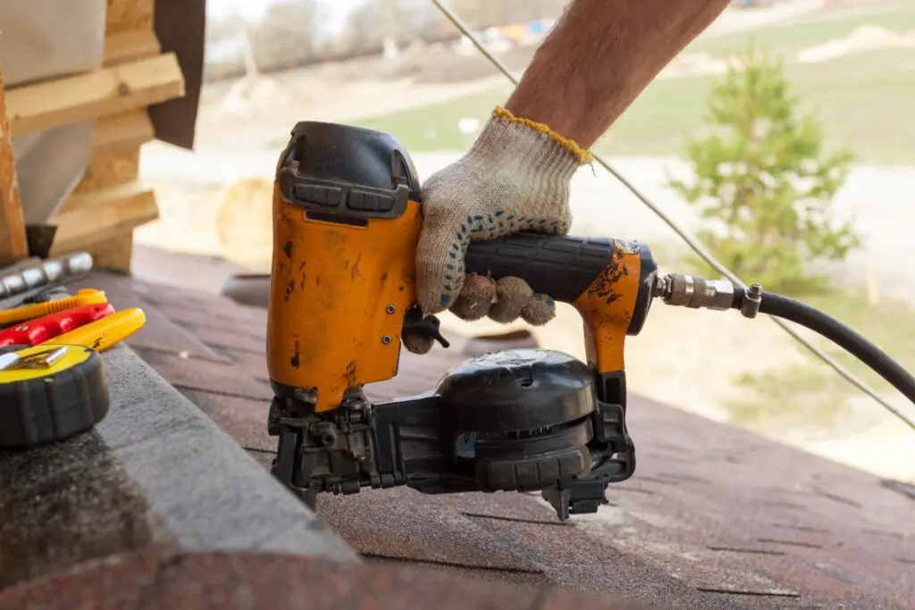 roofing tools worker using nailgun shingles roof