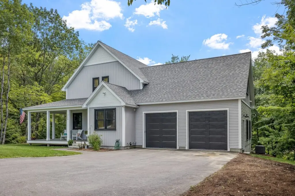 Modern custom new England colonial home with an American flag on a sunny day