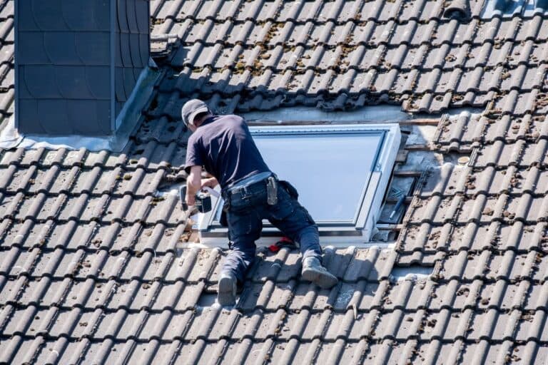 skylight installation worker installing window outside of big roof brown tiles