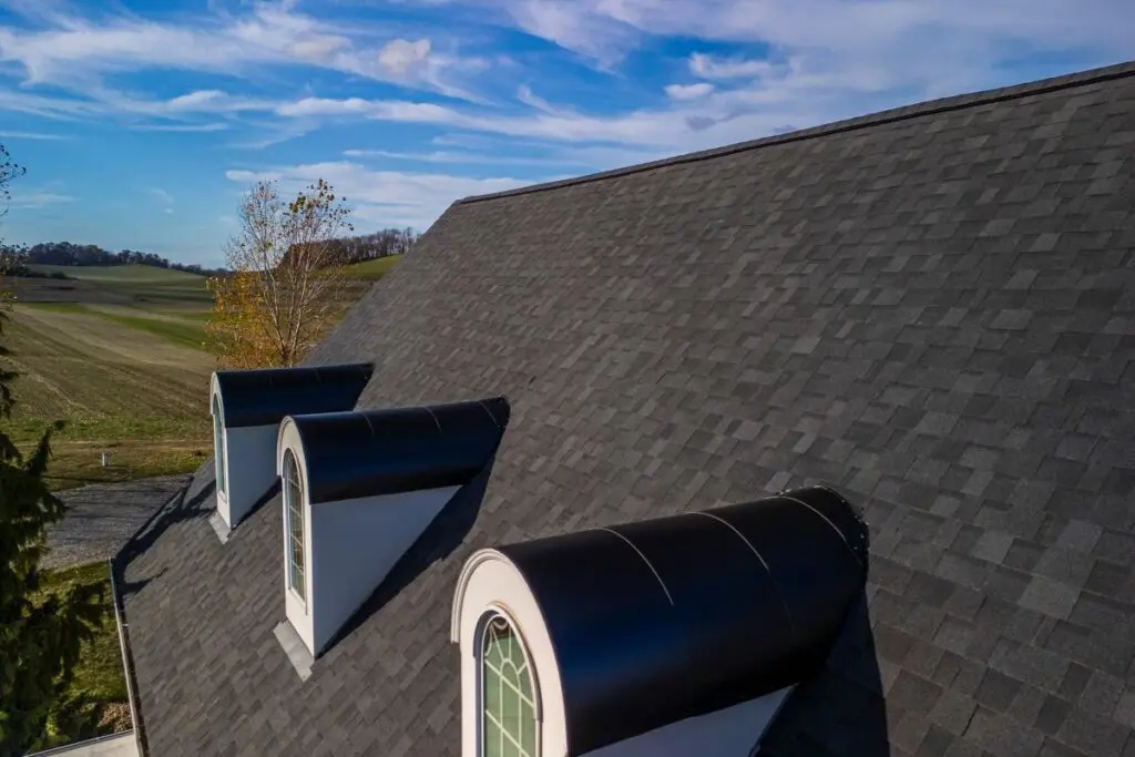 Keim Quality Roofing project dark grey roof blue sky big house