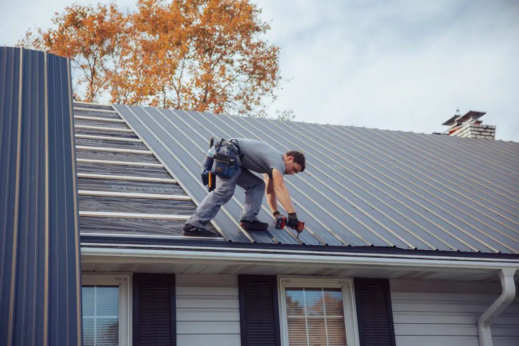 roof replacement cost worker replacing metallic roof