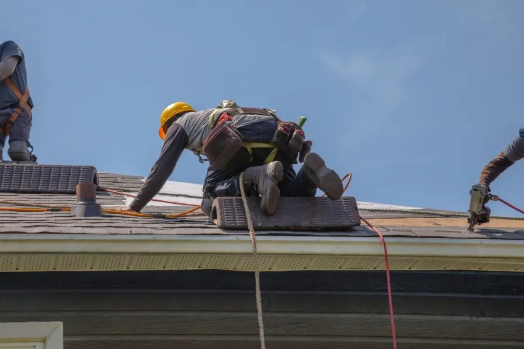 roof insurance claim worker installing new asphalt shingles
