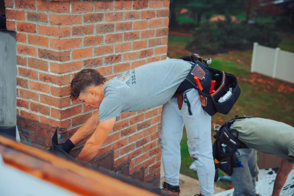 worker repairing flashing chimney