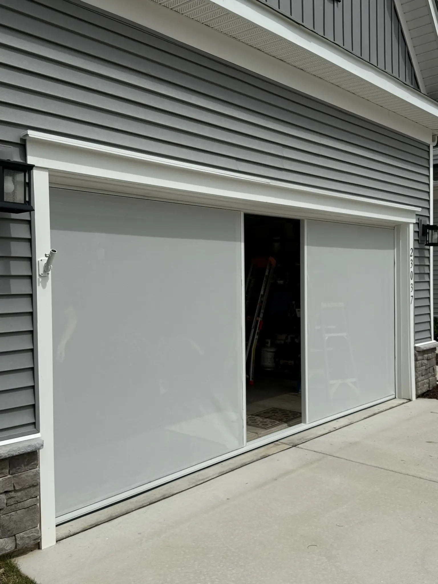 Modern white garage with frosted glass doors partially open, showing interior storage space.