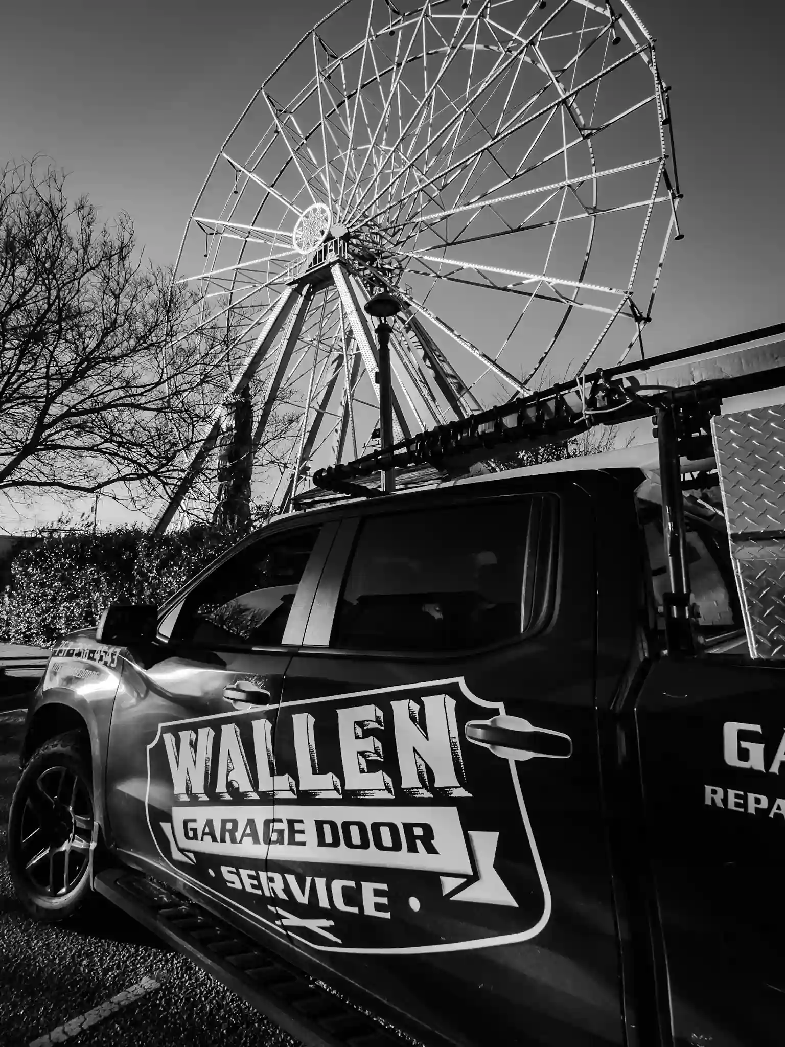 Wallen Garage Door Service truck parked beneath a large ferris wheel against clear sky.