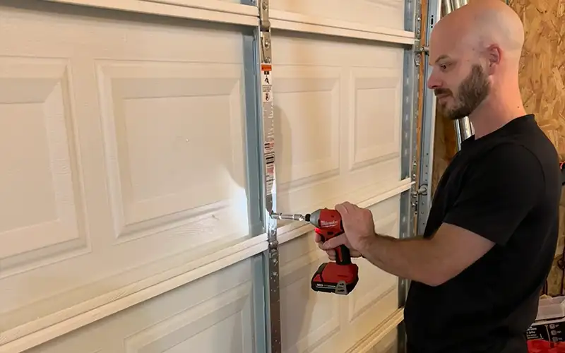 Technician securing panel hinges during garage door installation