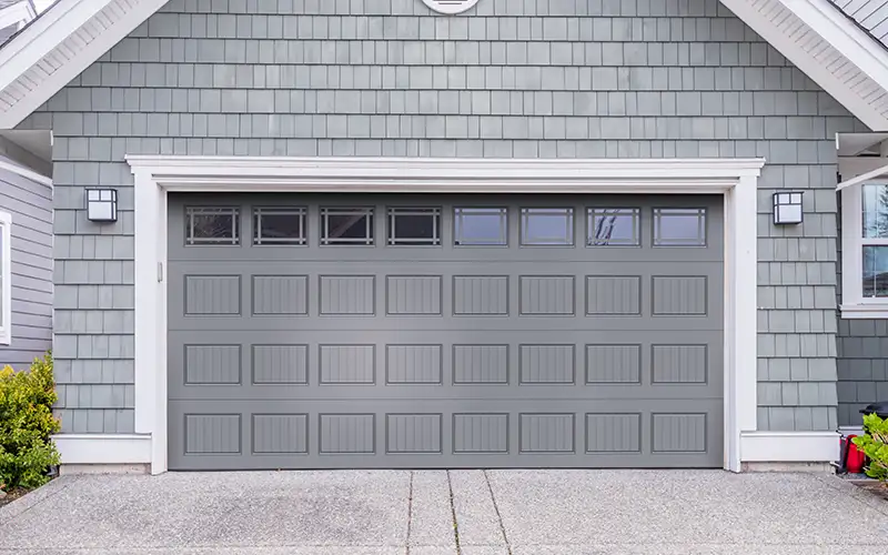 Modern gray residential garage door on home exterior in garage door panel replacement service