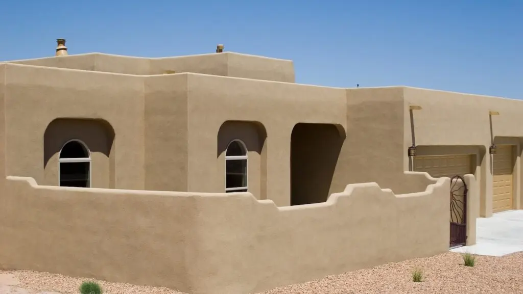 adobe home with stucco exterior and privacy wall