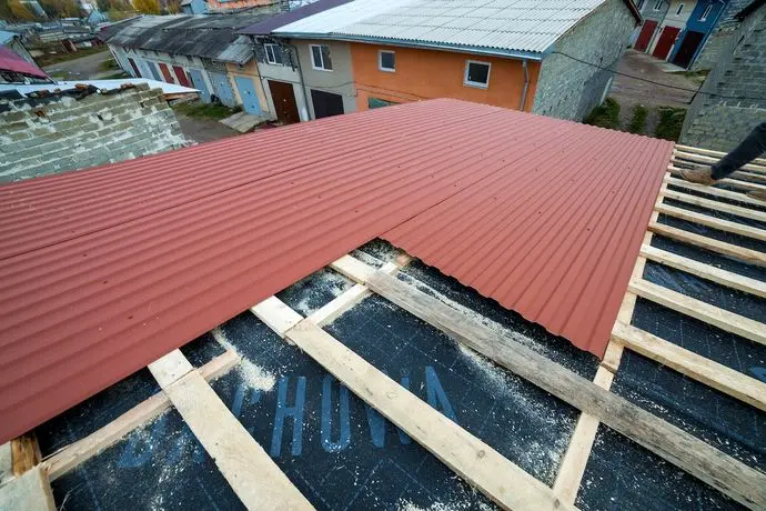 metal roof underlayment installation. red metal panels with underlayment.