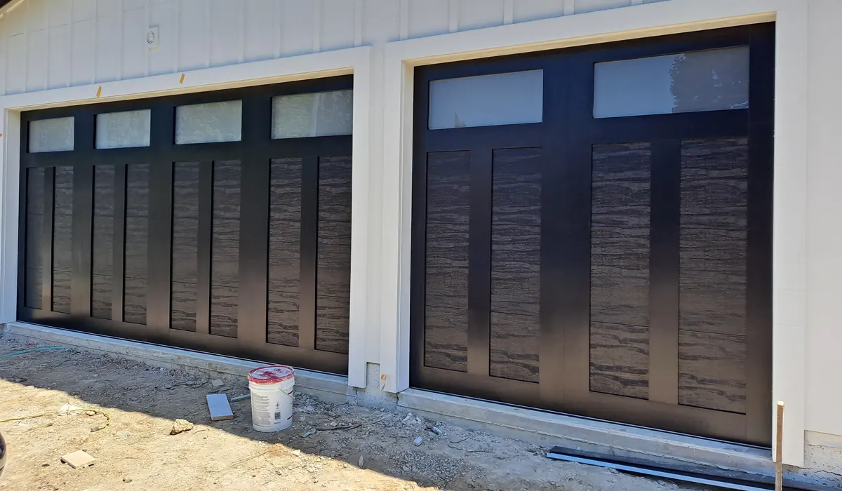 Black carriage-style garage doors with glass tops on a new white home