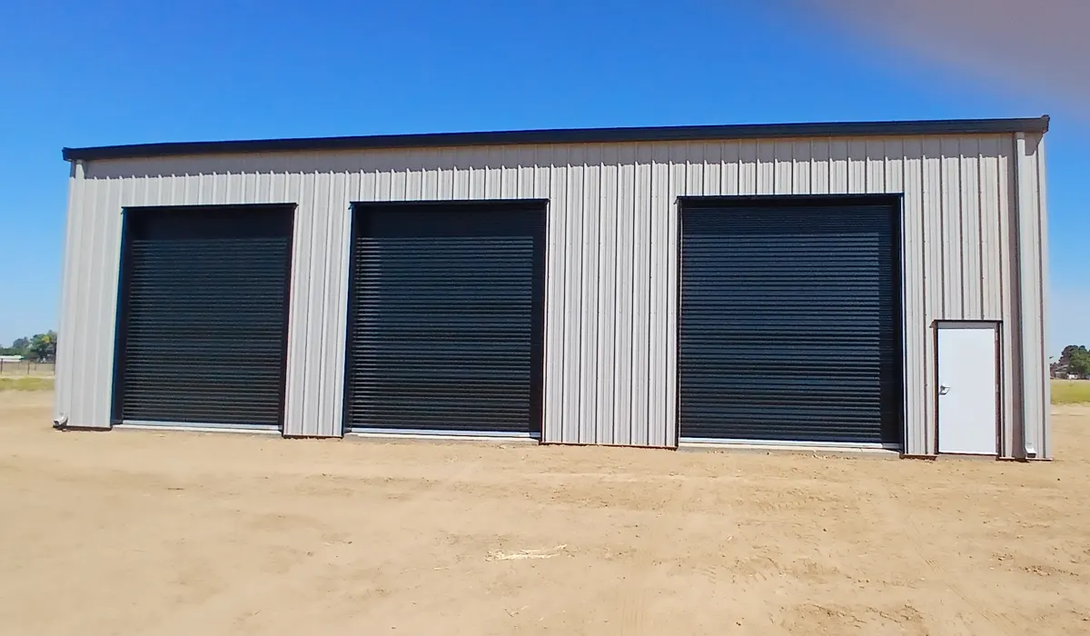 Three black roll-up doors on a commercial metal building
