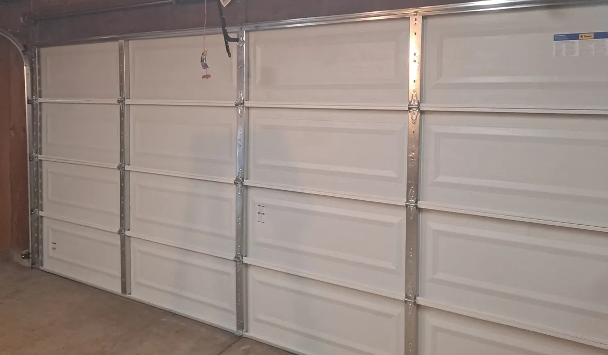 Inside view of a white sectional garage door showing its hinges, struts, rollers and tracks