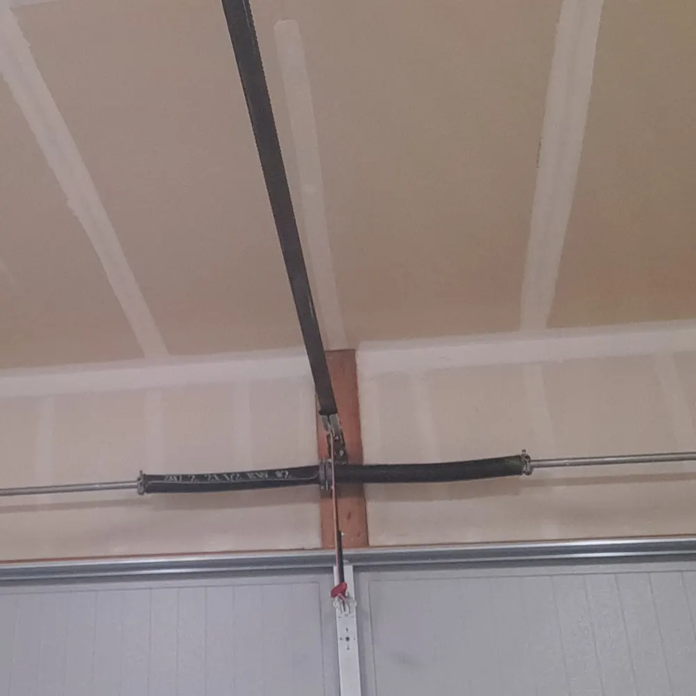 Technician adjusting the torsion spring above a garage door during a tune-up