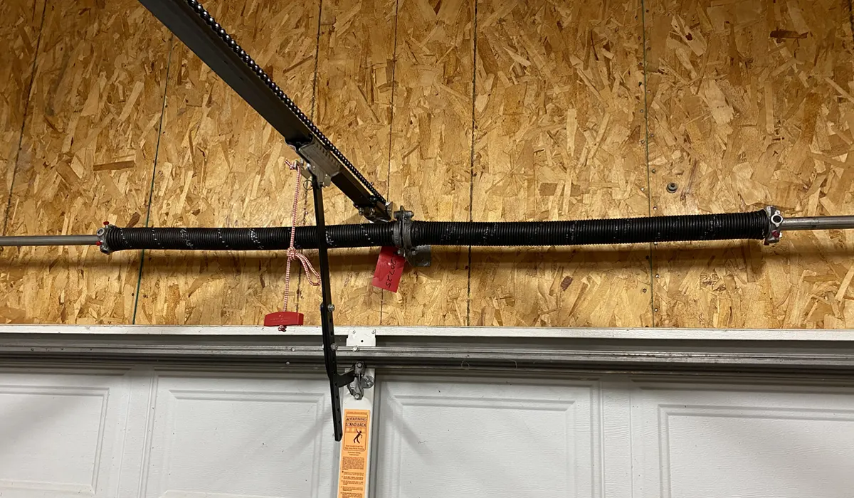 Torsion spring and lift cable mounted above a white garage door