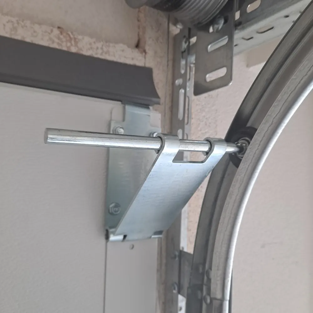 Top roller bracket and roller in the curved track of a garage door, below the cable drum