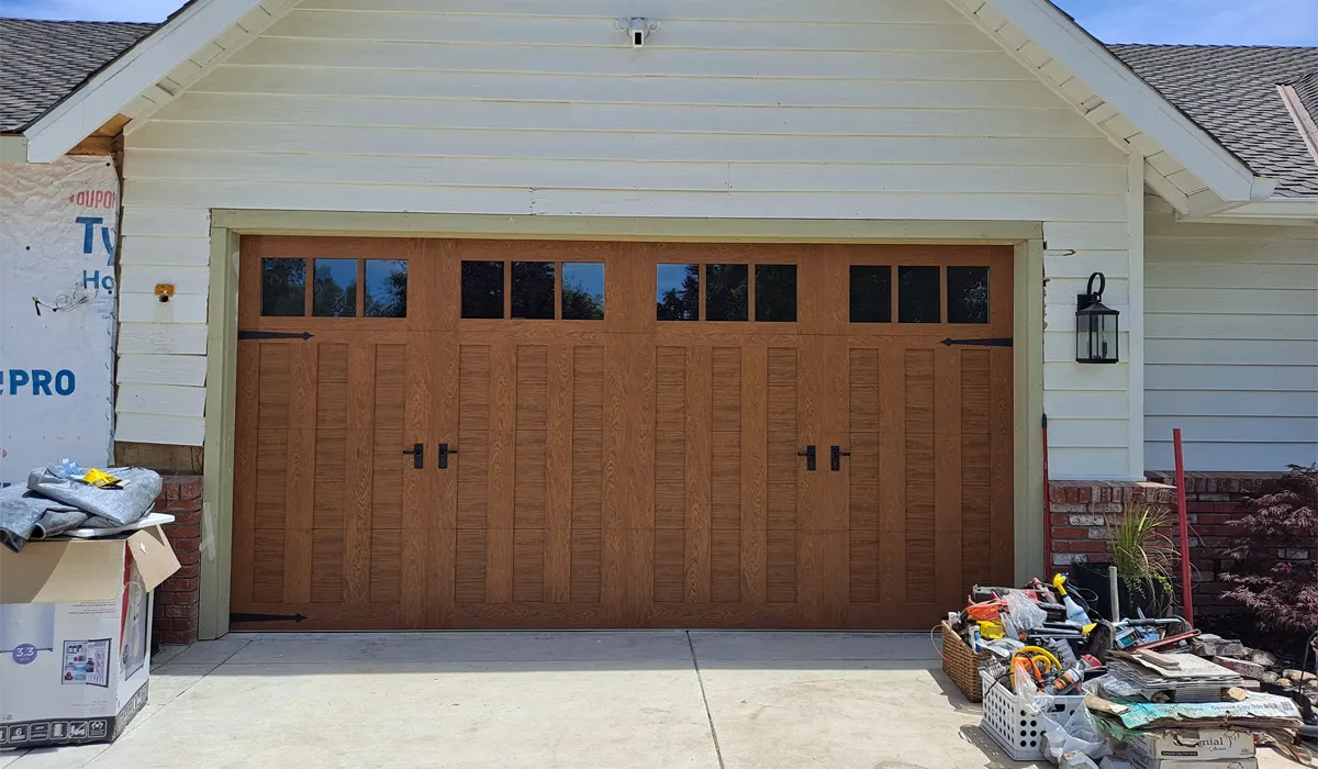 New wood-look carriage-style garage door just installed, with packaging still on the driveway
