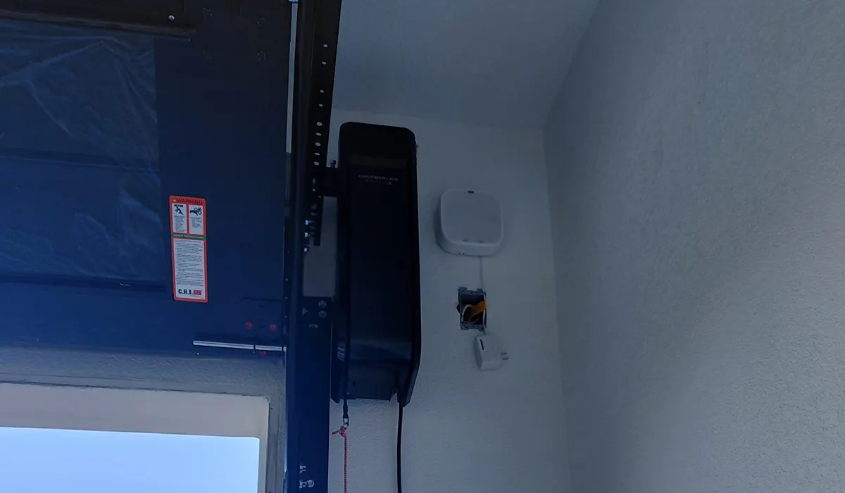 Wall-mounted garage door opener and control panel beside a garage door opening