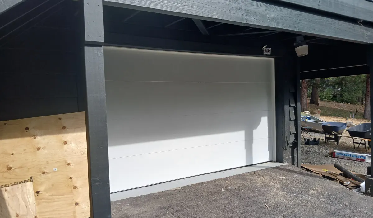 White flush-panel garage door closed inside a dark-trimmed garage