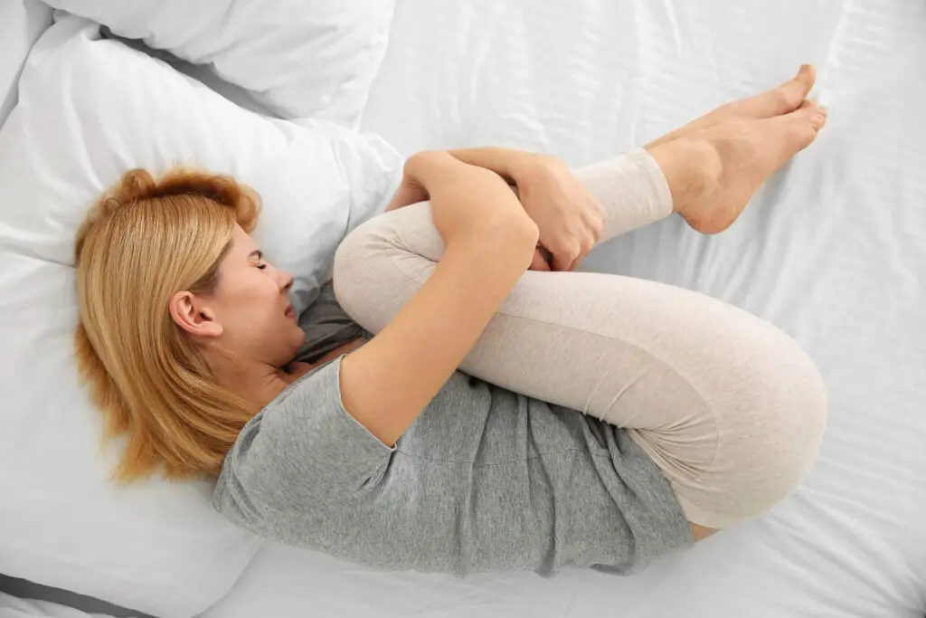 Young woman suffering from pain on bed
