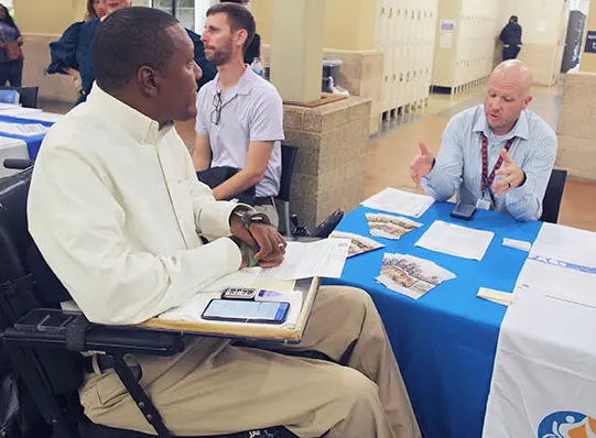 A man in a wheelchair talks with a vendor at the disAbility Expo