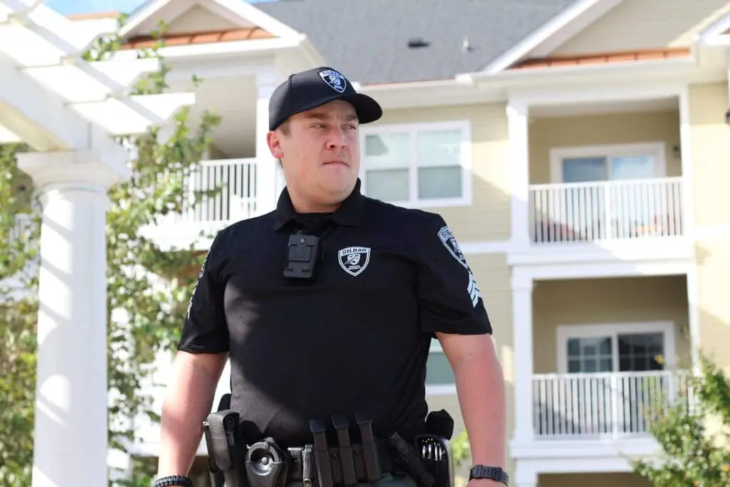 A uniformed security guard standing outside a building