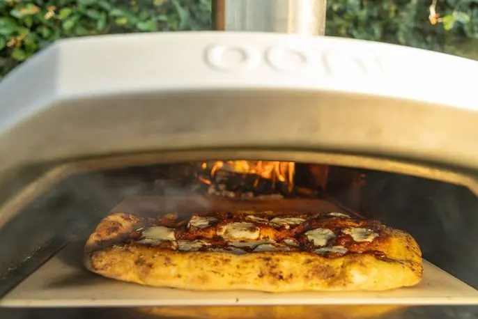 Wood-fired pizza oven in action at an outdoor team-building catering event by Handheld Catering