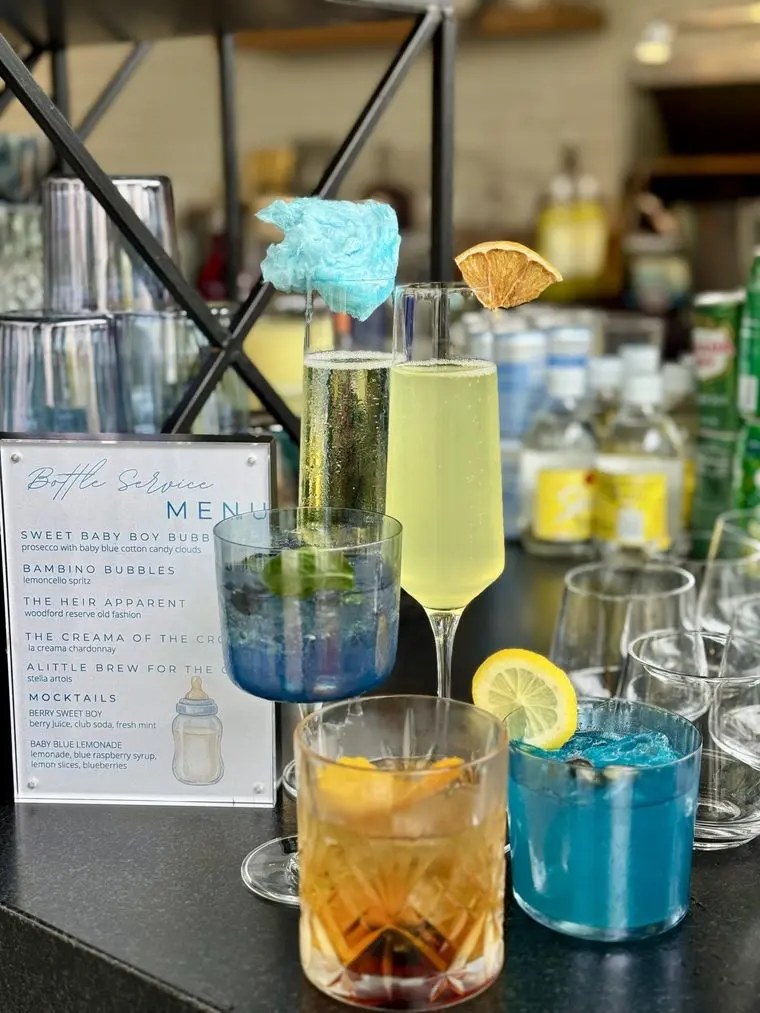Handheld Catering baby shower mocktail bar with signature blue and citrus drinks, a cotton candy topped sparkling pour and a printed drinks menu