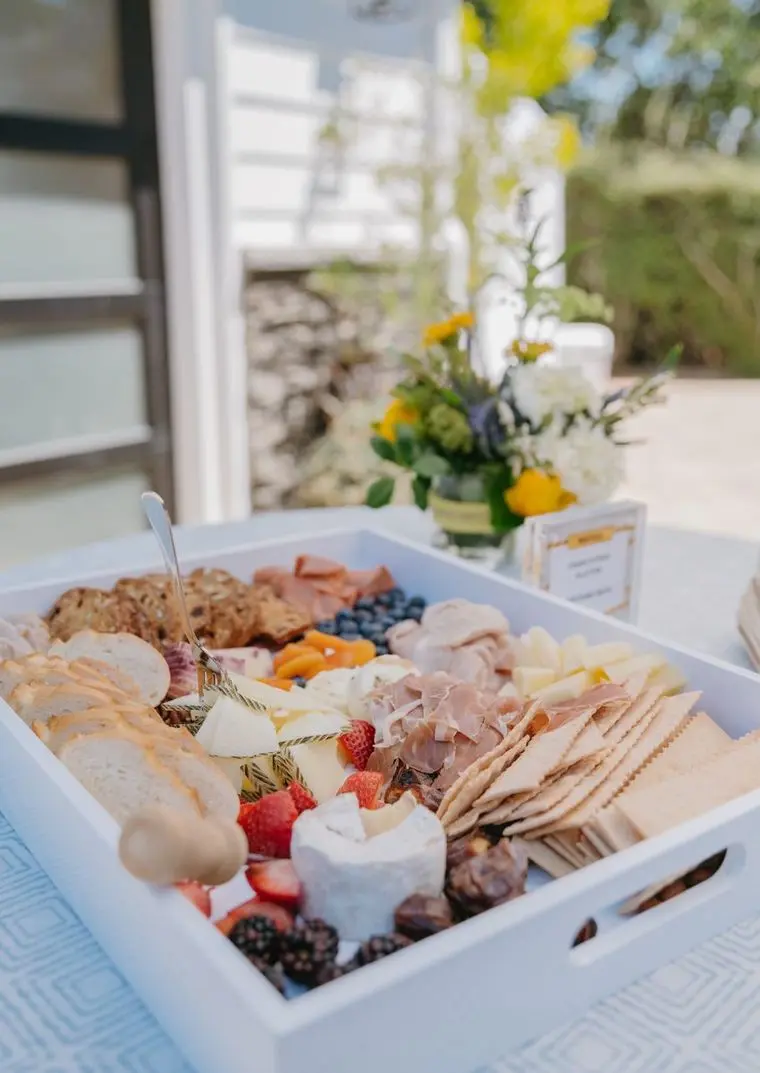 Outdoor charcuterie box with prosciutto, cheeses, berries, and fresh bread by Handheld Catering
