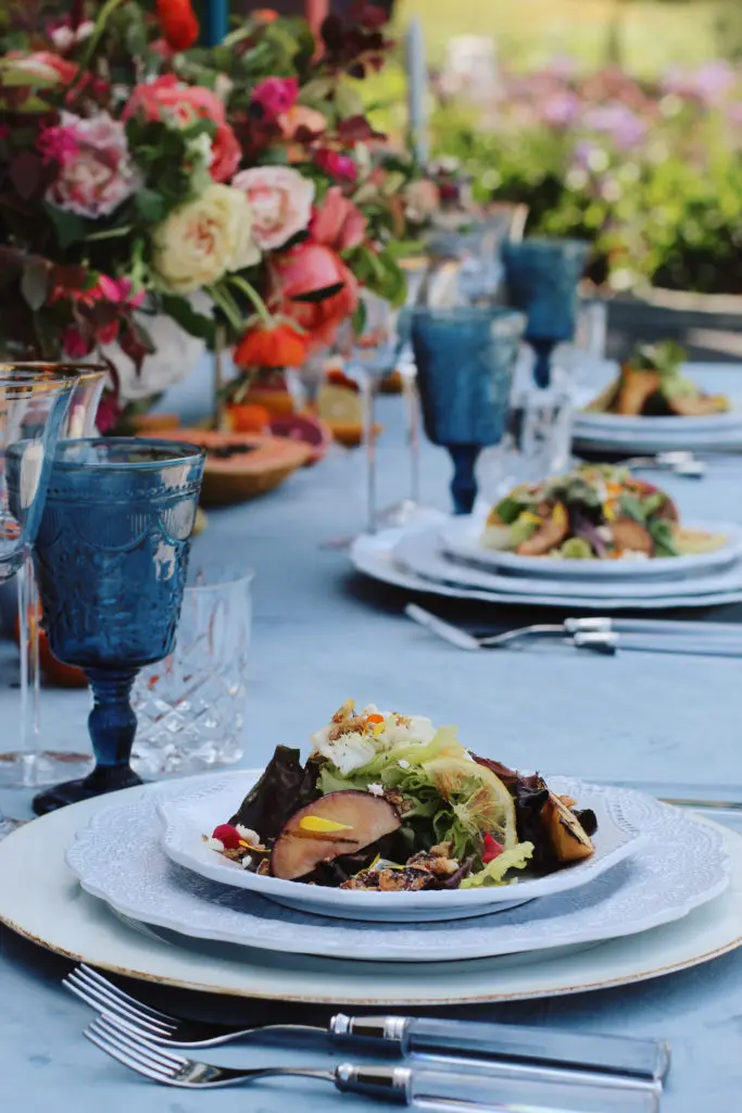 Grilled stone fruit and Bibb lettuce salad plated on a garden table