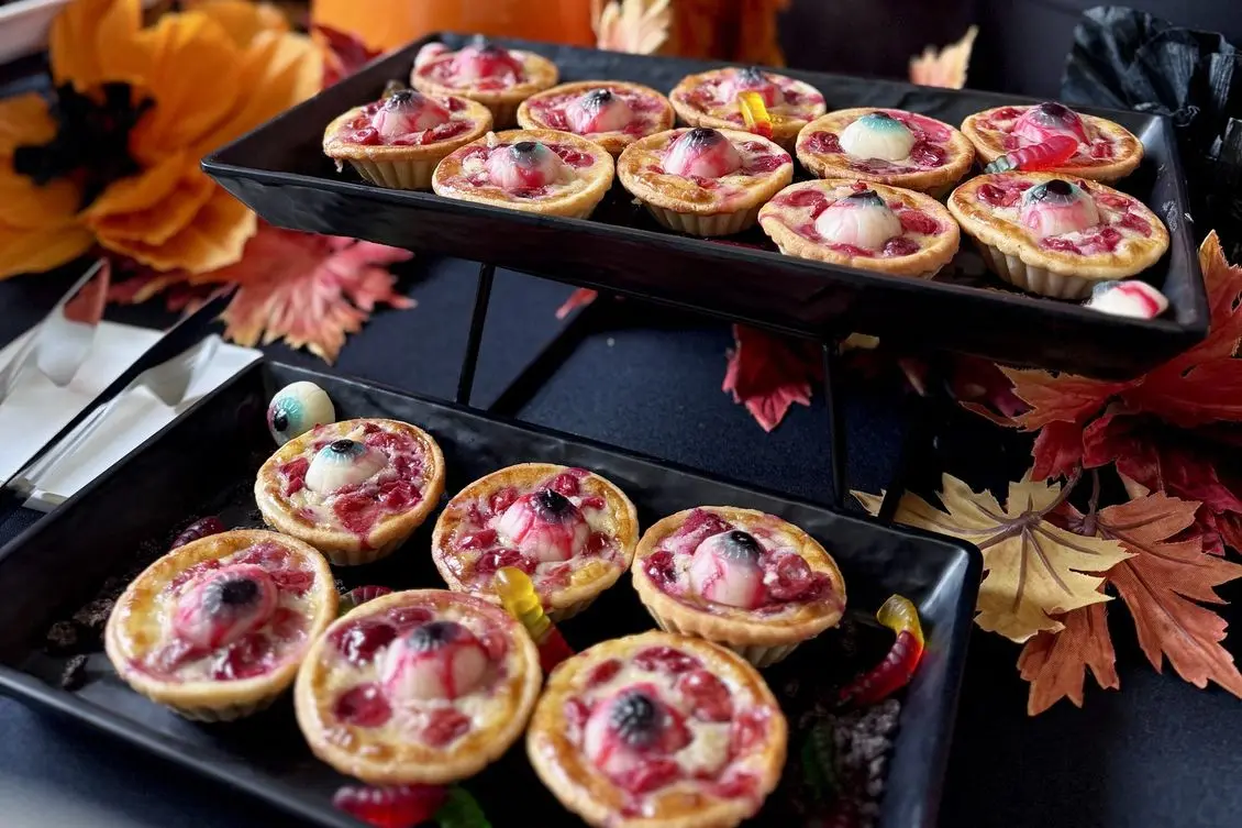 Handheld Catering Halloween eyeball cherry tarts on tiered black trays at a corporate lunch