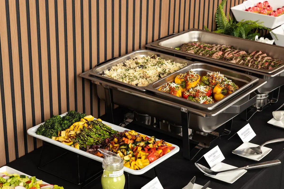 Handheld Catering corporate holiday lunch buffet with chafing dishes and printed cards labeling the lemon risotto gluten free and the stuffed peppers gluten free and vegan