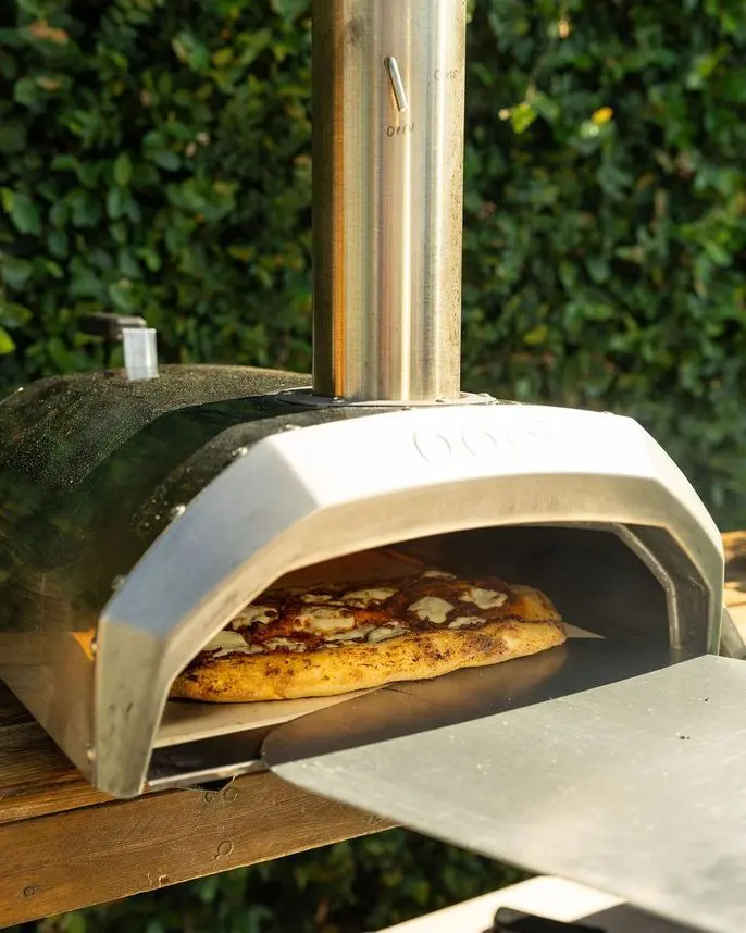 Close-up of pizza baking in a portable wood-fired oven at a corporate team-building event