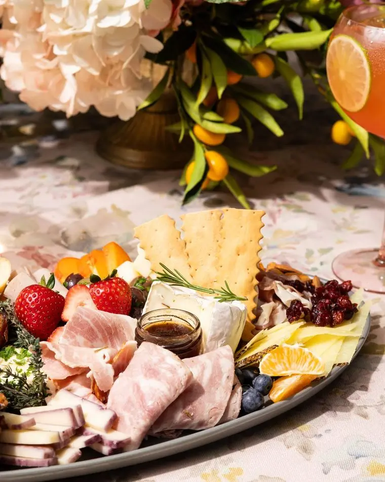 Professional spring charcuterie platter with meats, brie, strawberries, and crackers by Handheld Catering