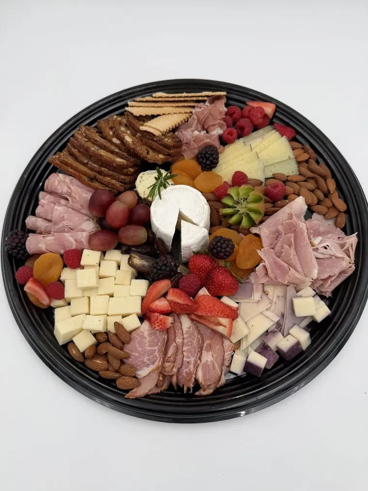 Handheld Express Premium Charcuterie Platter with cured meats, brie, cubed cheeses, fresh berries, grapes, kiwi, dried apricots, almonds and crackers on a black catering tray