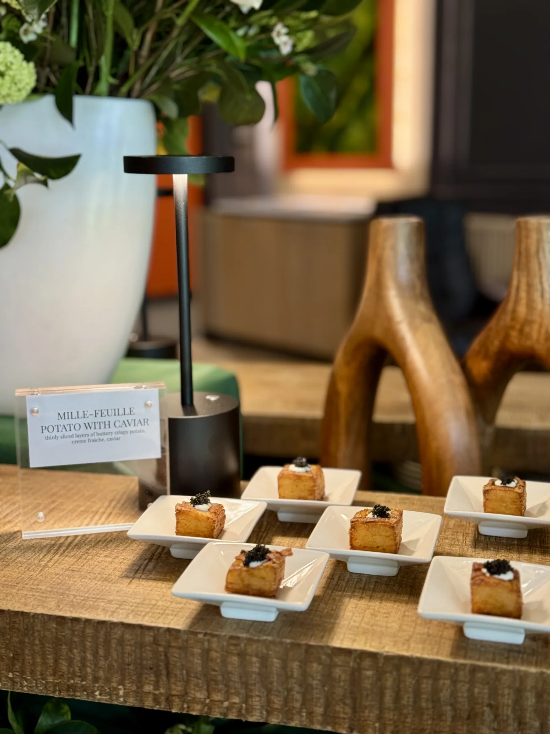 Mille-Feuille Potato with Caviar bite-size hors d'oeuvres arranged on white plates with acrylic menu card at Handheld Catering's Santa Clara headquarters ribbon cutting celebration