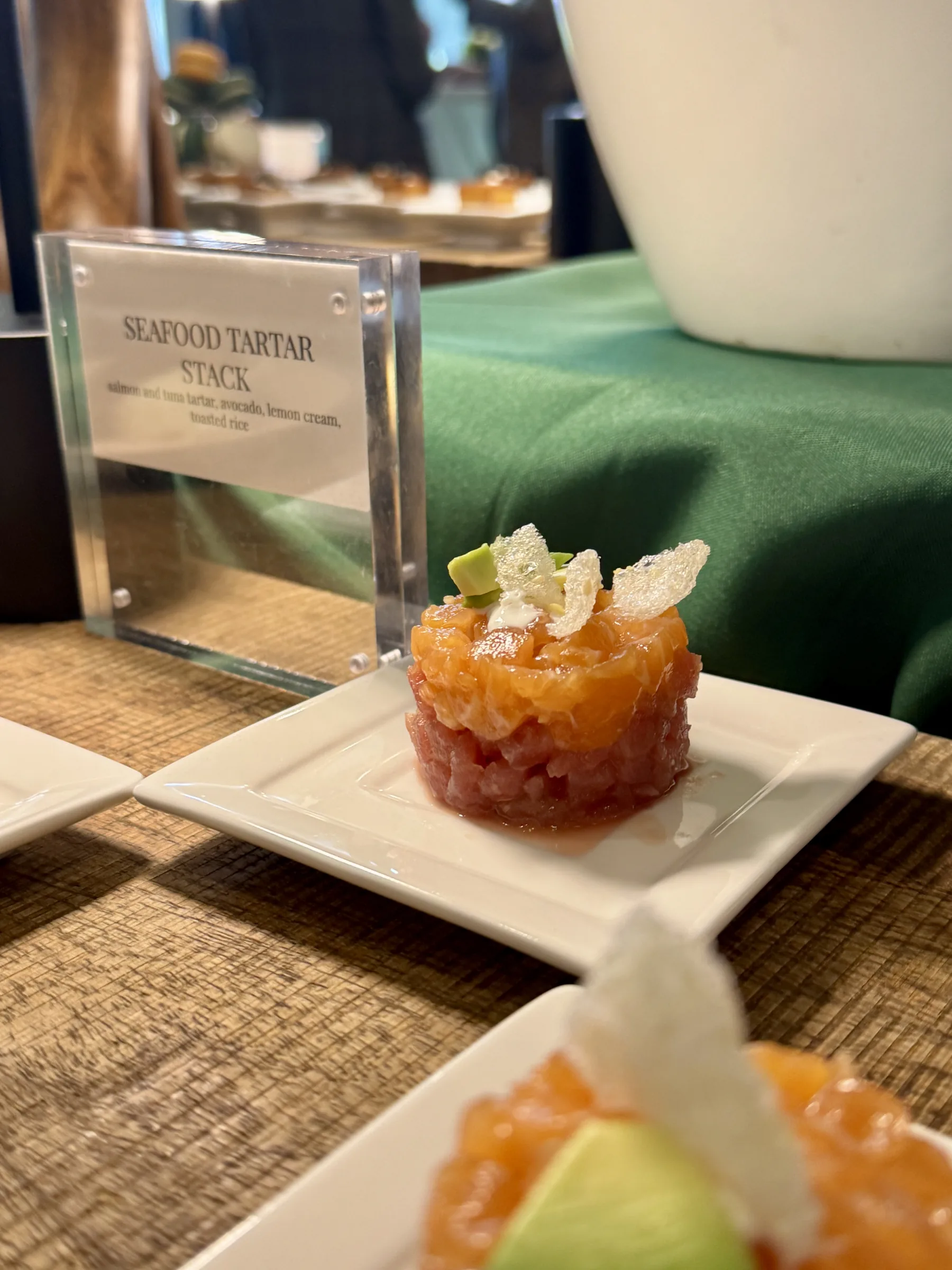 Seafood Tartar Stack with avocado garnish plated on white china with acrylic menu card at Handheld Catering's Santa Clara headquarters grand opening celebration