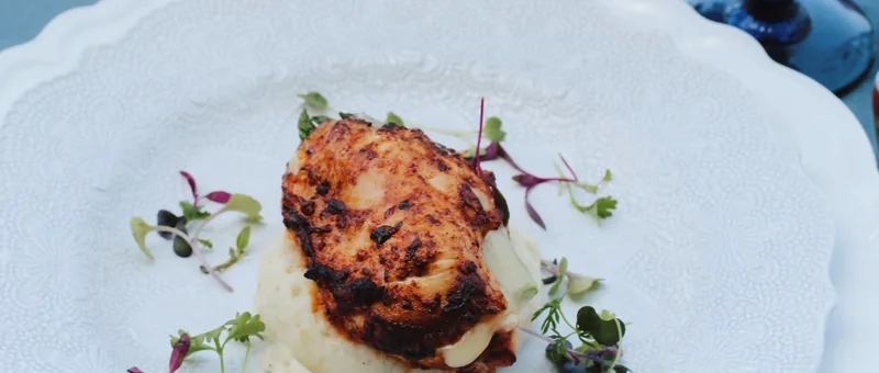 Plated asparagus stuffed chicken on scalloped white plate at a Bay Area wedding by Handheld Catering