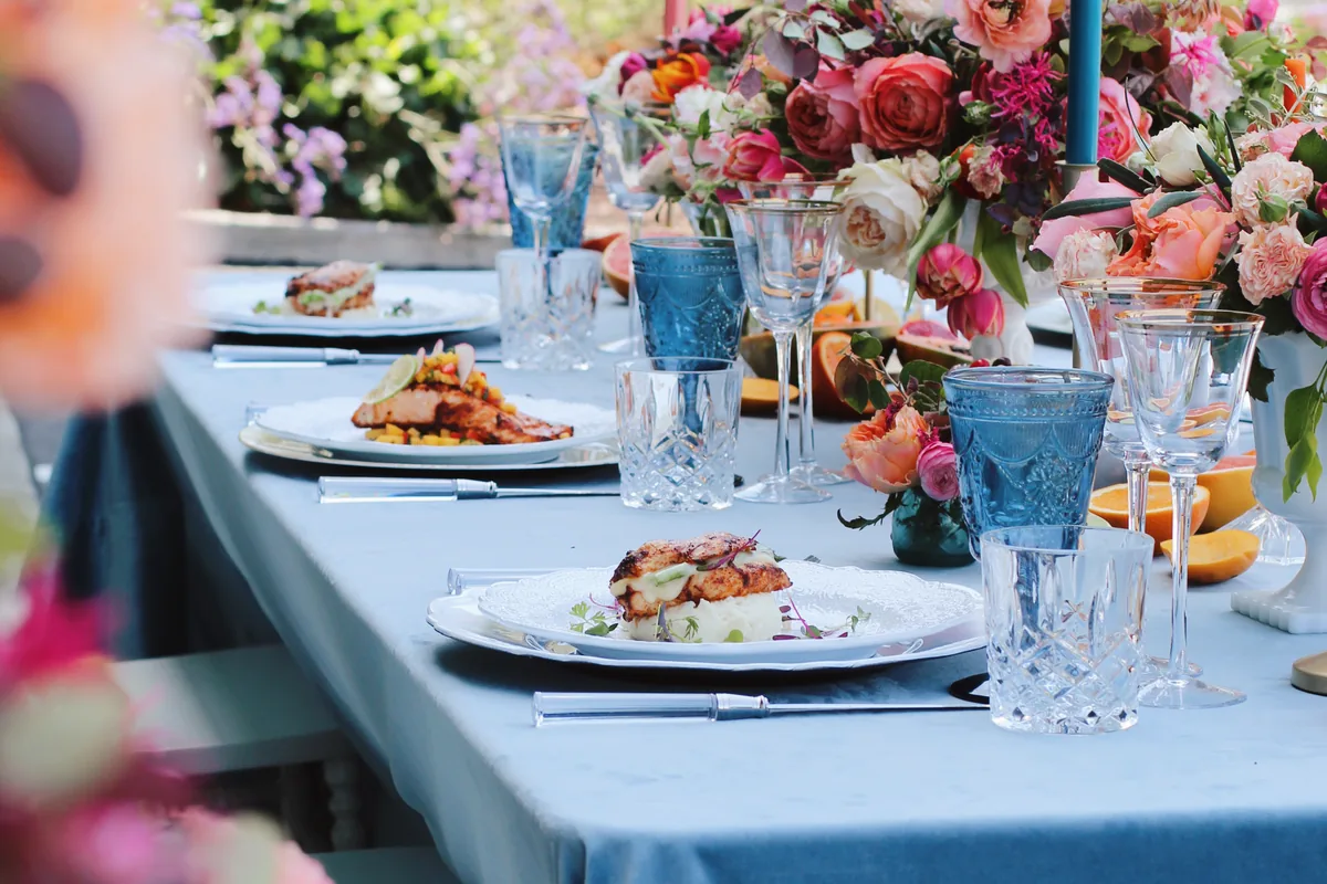 Outdoor wedding table setting with plated entrees and floral arrangements catered by Handheld Catering