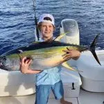 Boy Holding a Yellow Fin Fish on Boat