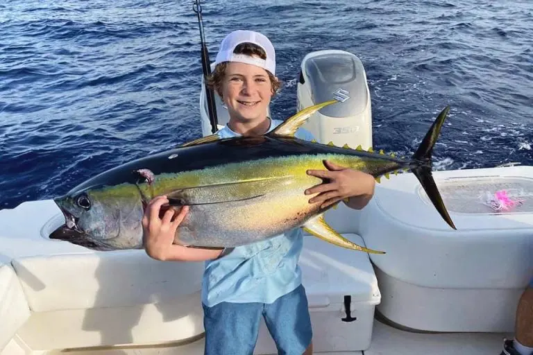 Boy Holding a Yellow Fin Fish on Boat