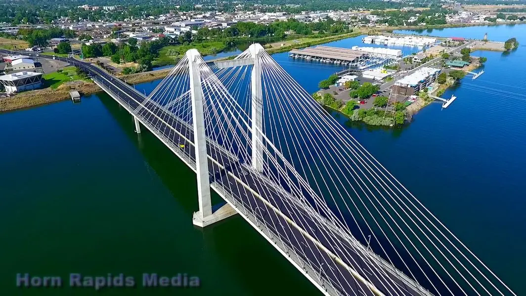 Alpine Roofing Bird's eye view of a white-color suspension bridge over a river.