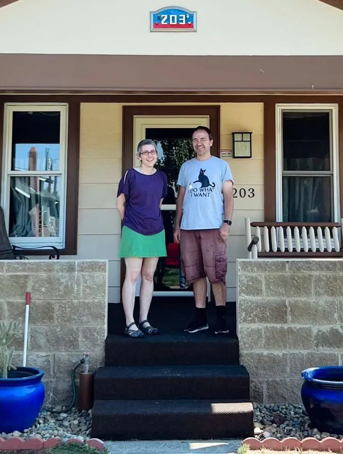 Two homeowners smiling on the front steps of their craftsman bungalow