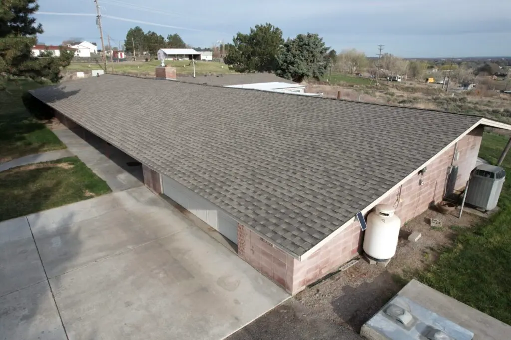 Kennewick WA roofing project photo featuring a brick home with newly installed dark gray shingles.