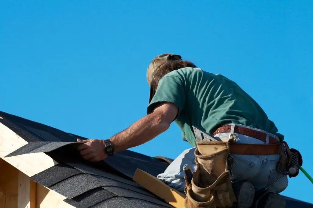 man installing roof shingles