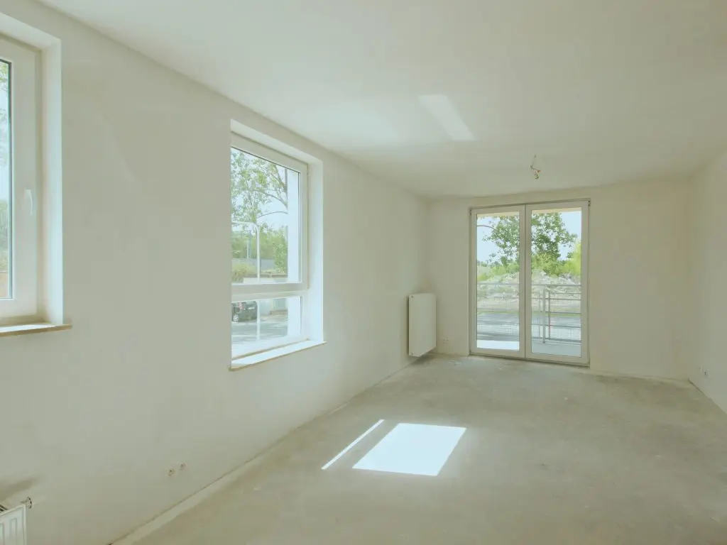 Bright empty room with large windows and sliding door in a new home.