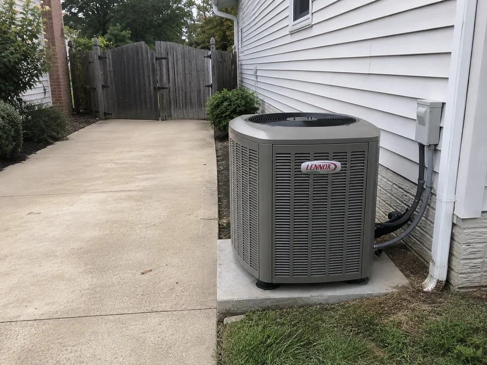 Outdoor Lennox air conditioning unit beside a white house on a concrete pad.
