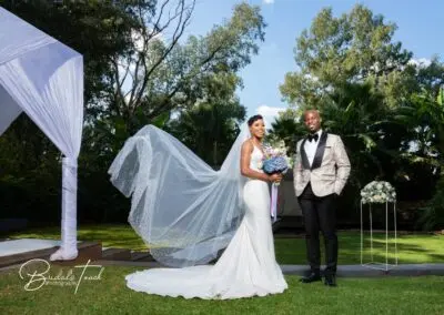 Bride and groom smile under a canopy at The Garden Venue wedding venue on a sunny day.